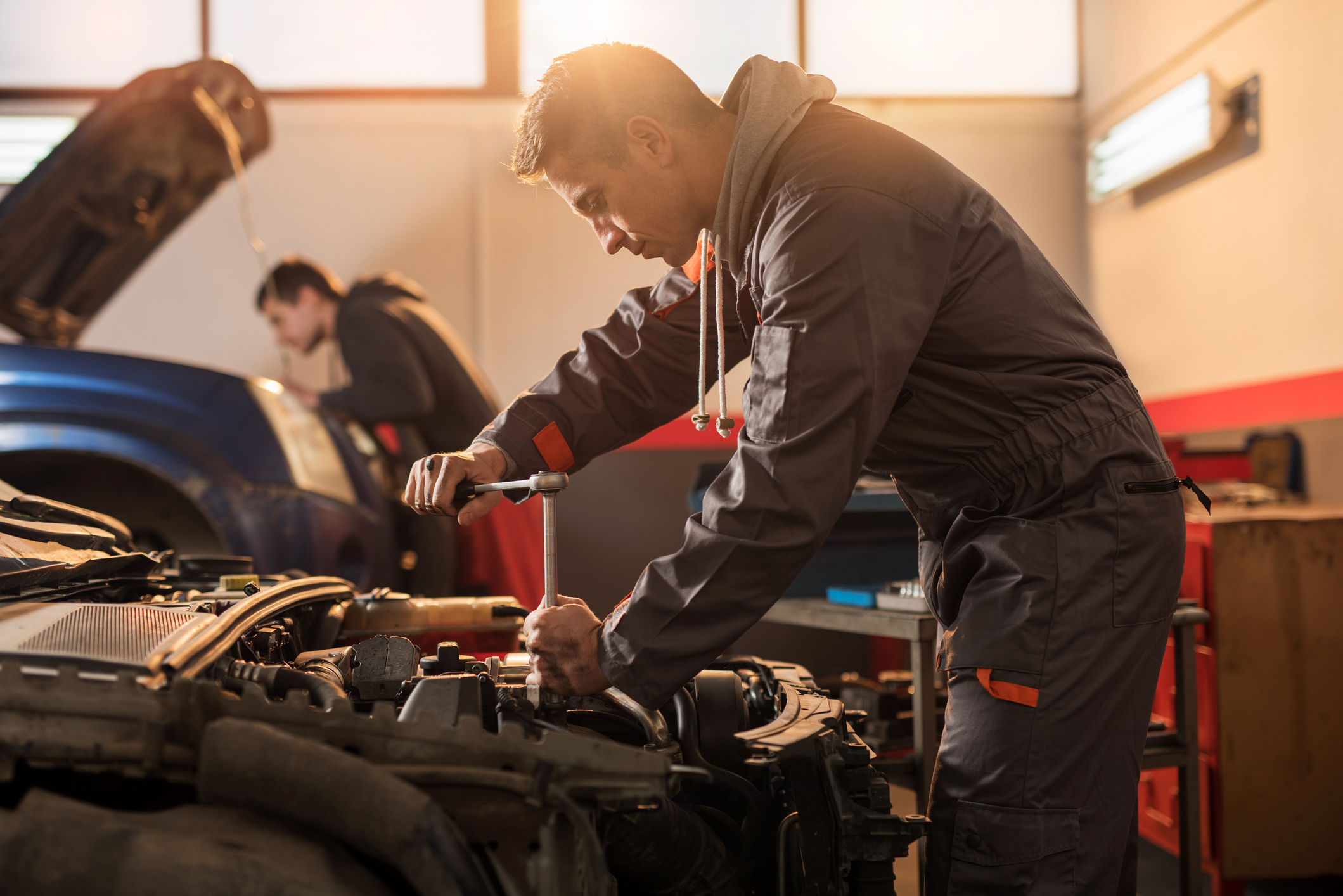 Auto mechanic working on a car engine in repair shop