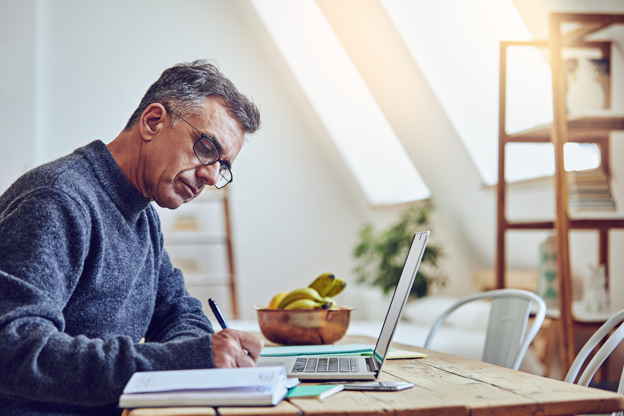 A person at a laptop holding a pen.