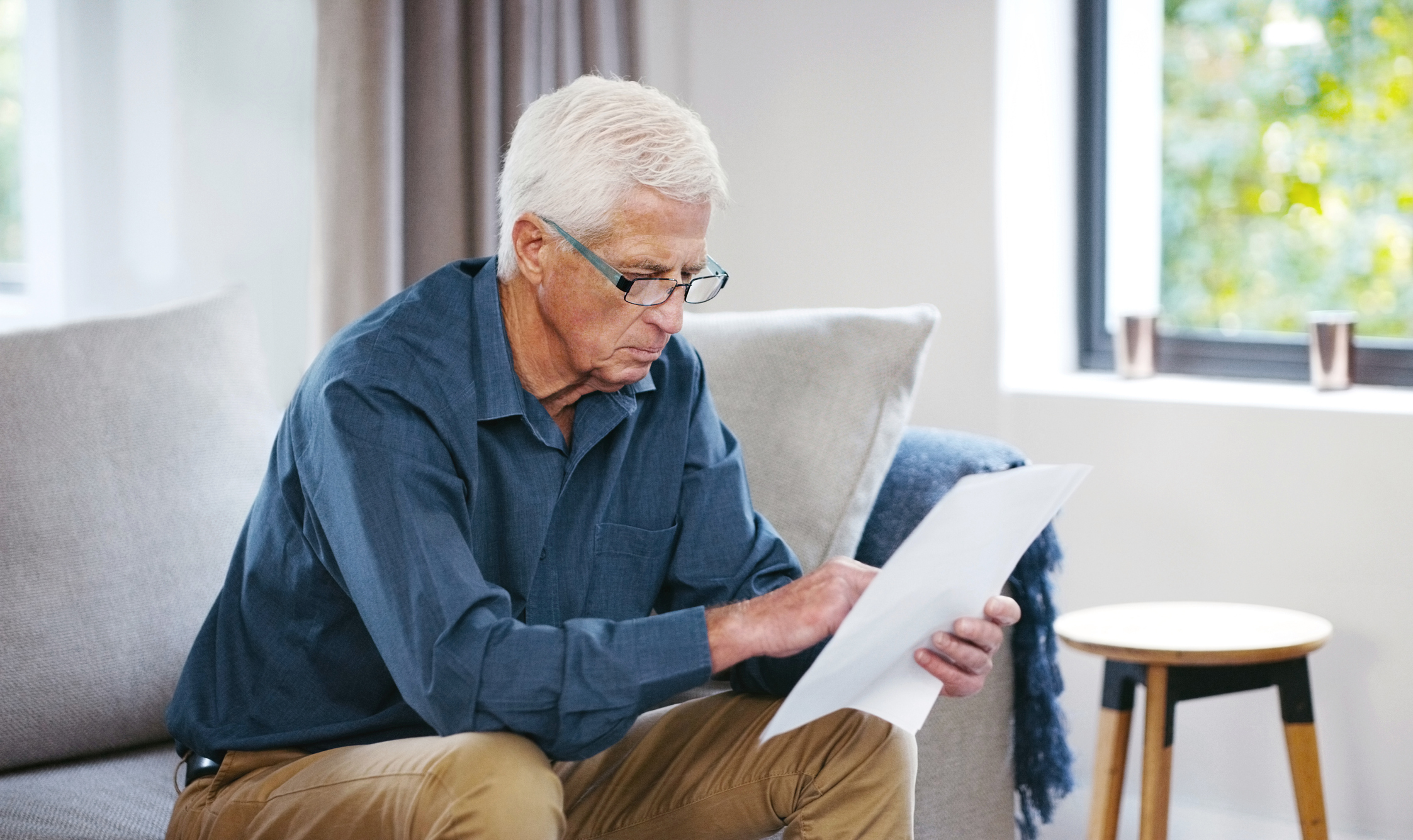 A person sitting on a couch holding a document.