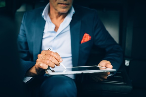 A person in a car signing a digital tablet.