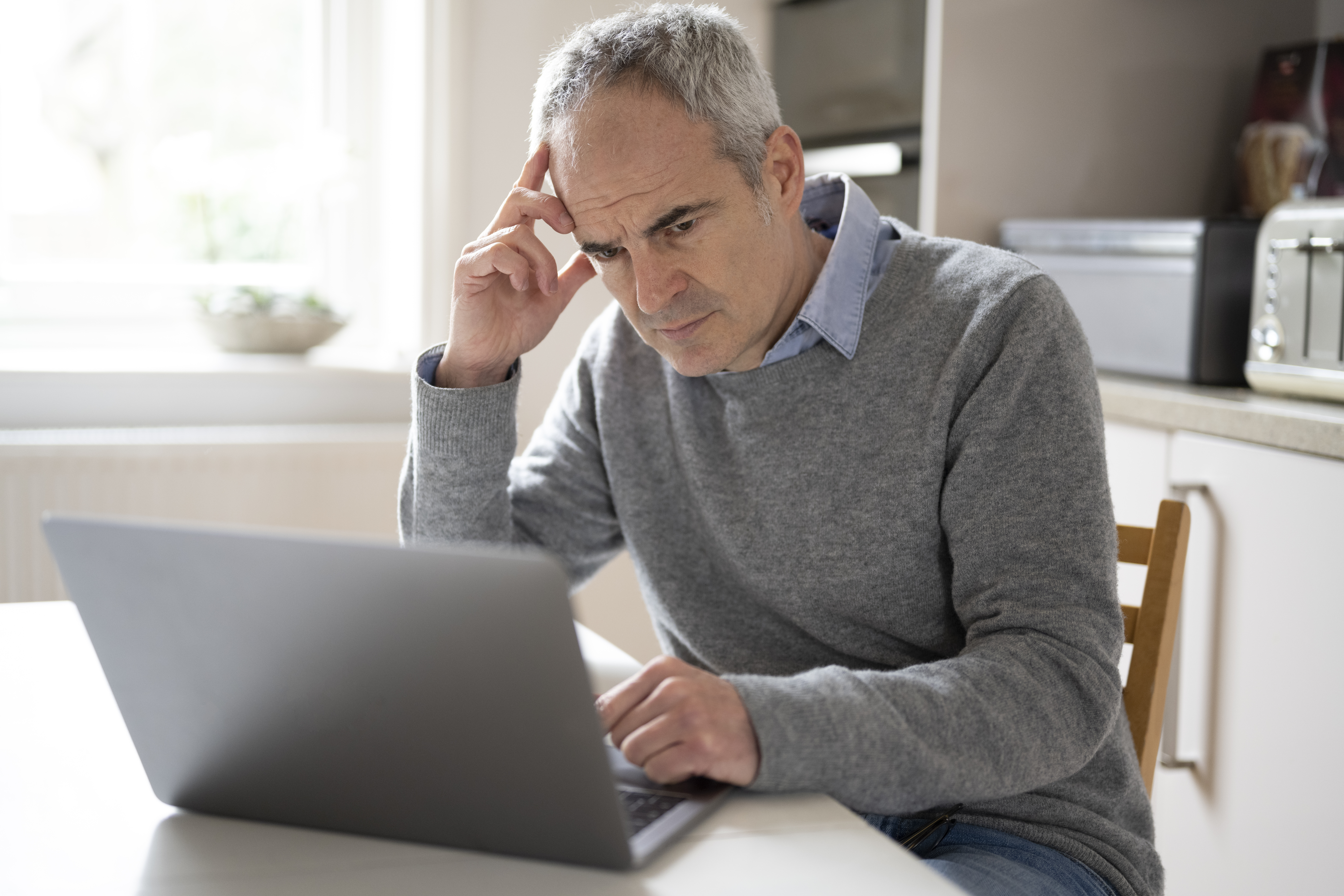 A person with a serious expression at a laptop.