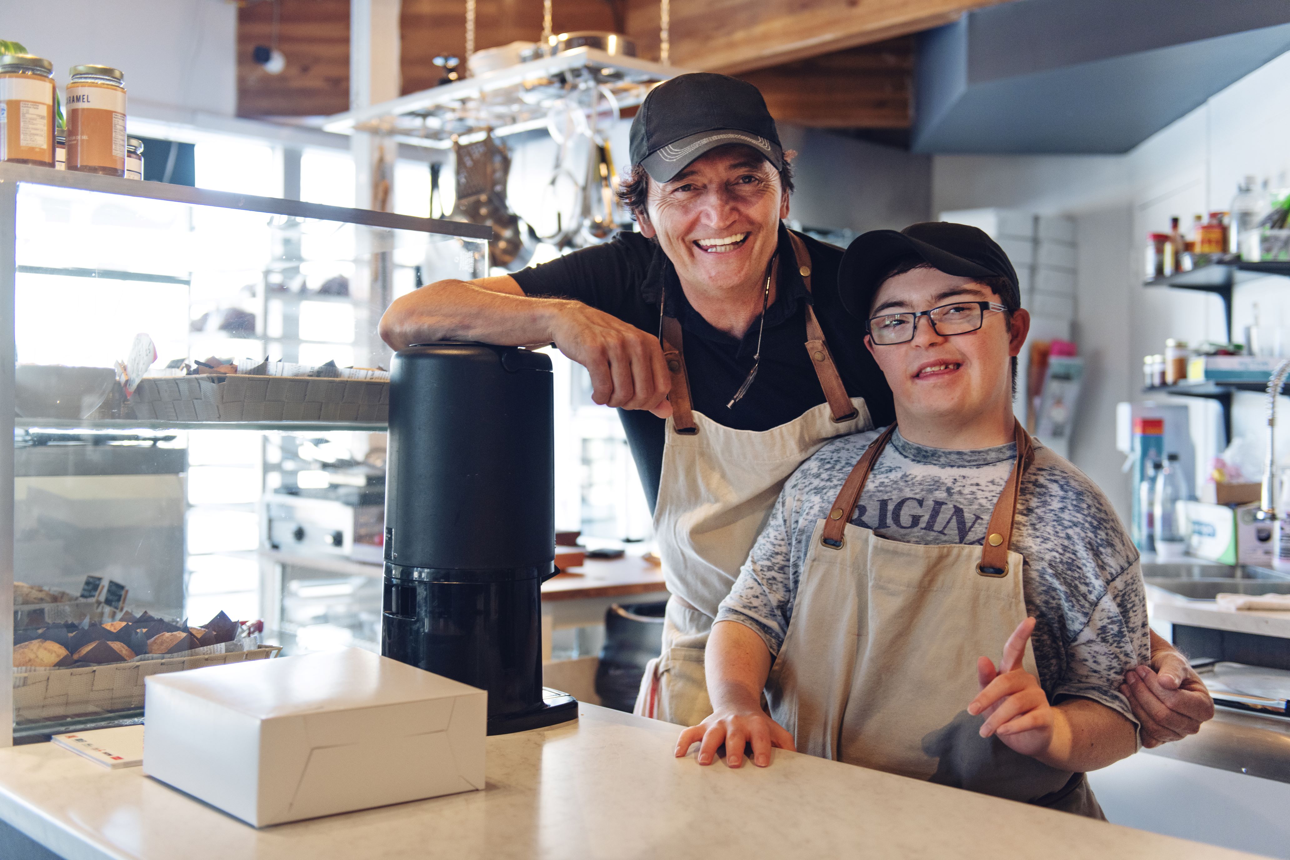 Two people at the counter in a coffee/bakery shop.