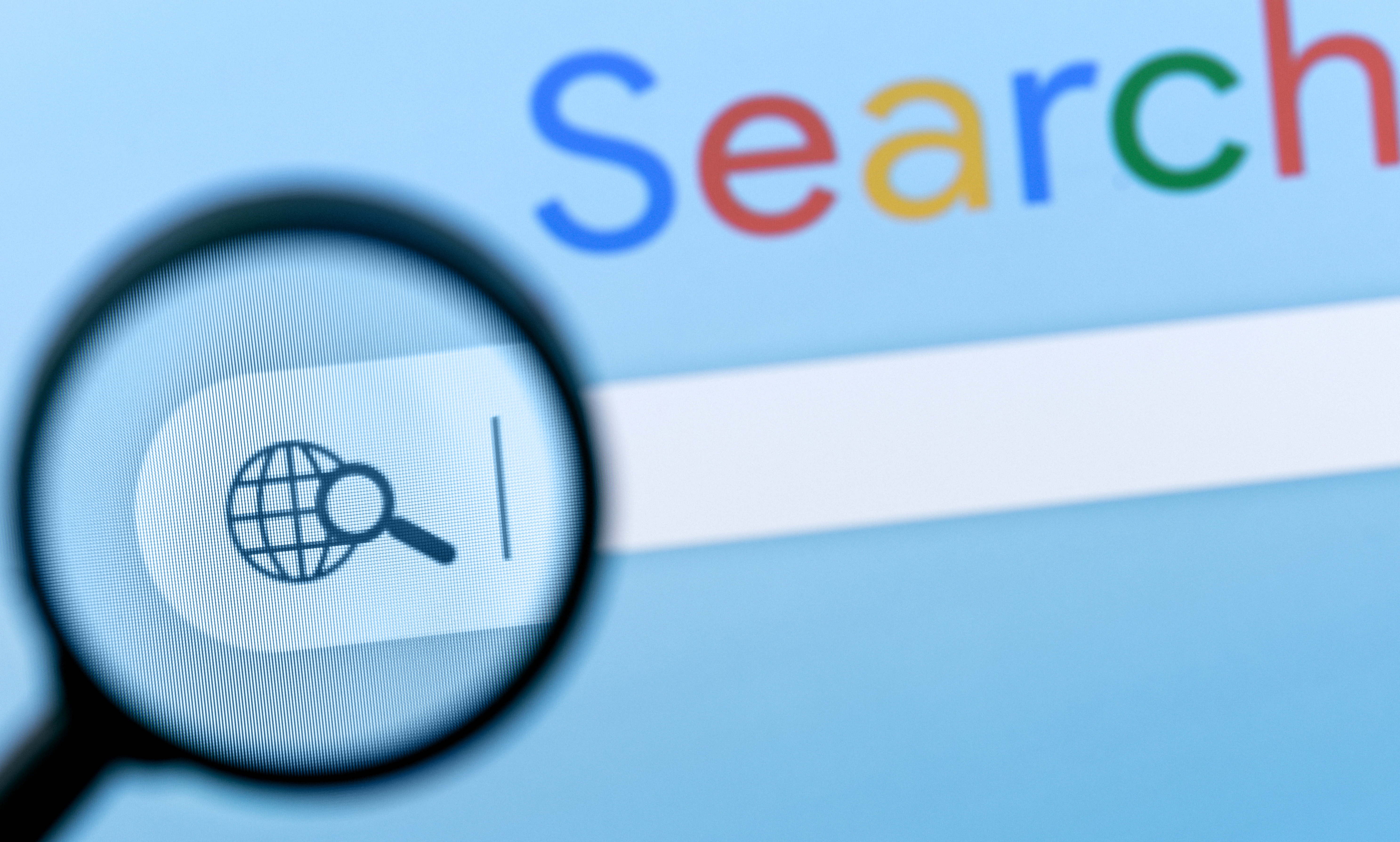 A magnifying glass looking at a search bar on a computer.