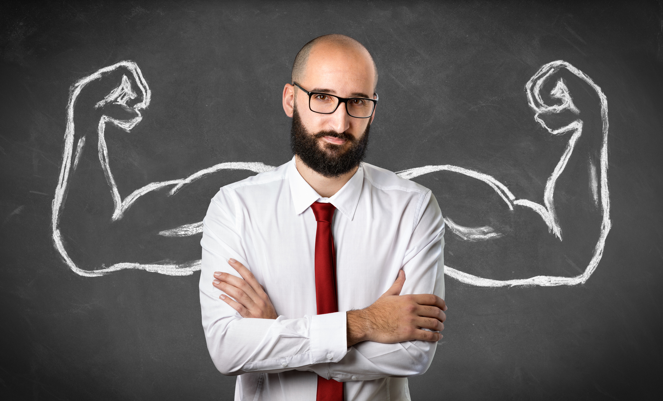 Someone is standing in front of a chalkboard on which are drawn muscular arms.