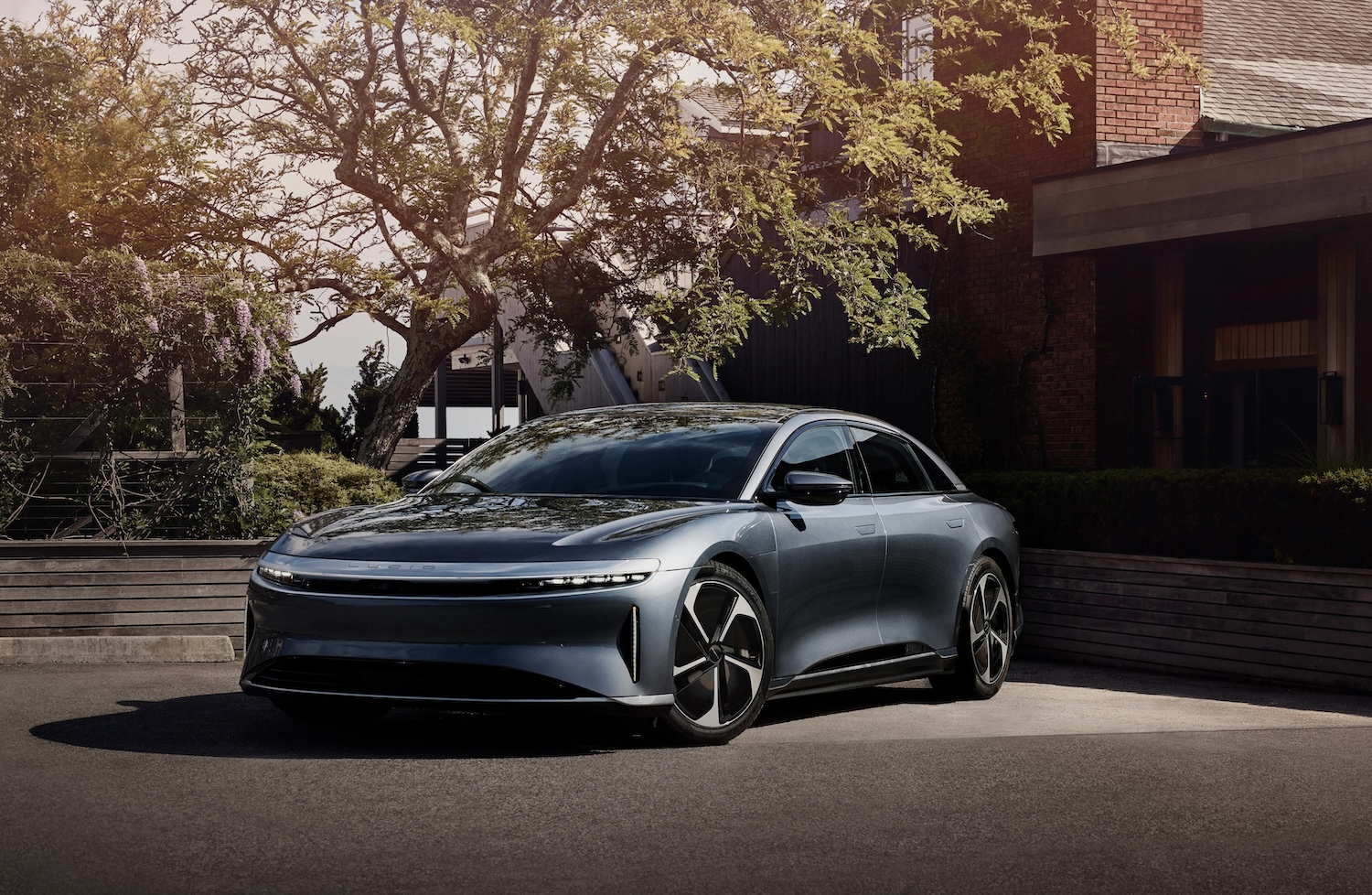 A Lucid Air Pure, an entry-level version of the Air electric luxury sedan, parked in front of a house.