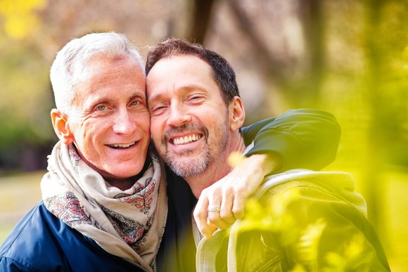 A couple is outdoors, smiling. 