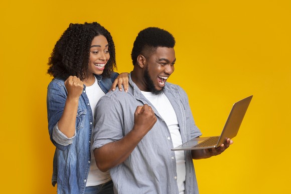 A happy couple looks at a laptop computer.