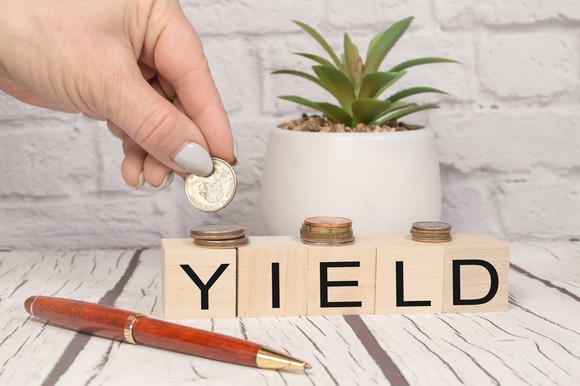 A person stacking coins on wooden blocks that read "YIELD."
