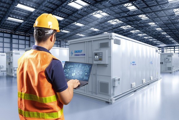 A person working on a laptop computer next to a container that reads "energy storage system."