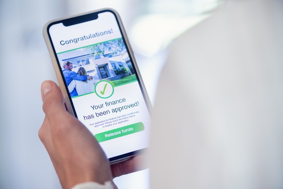 A man looking at a loan approval announcement on a smartphone.