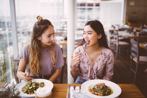 Two woman eating salad at a restaurant. 