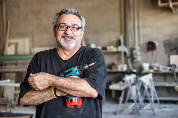 Someone is smiling in a workshop, holding a drill.