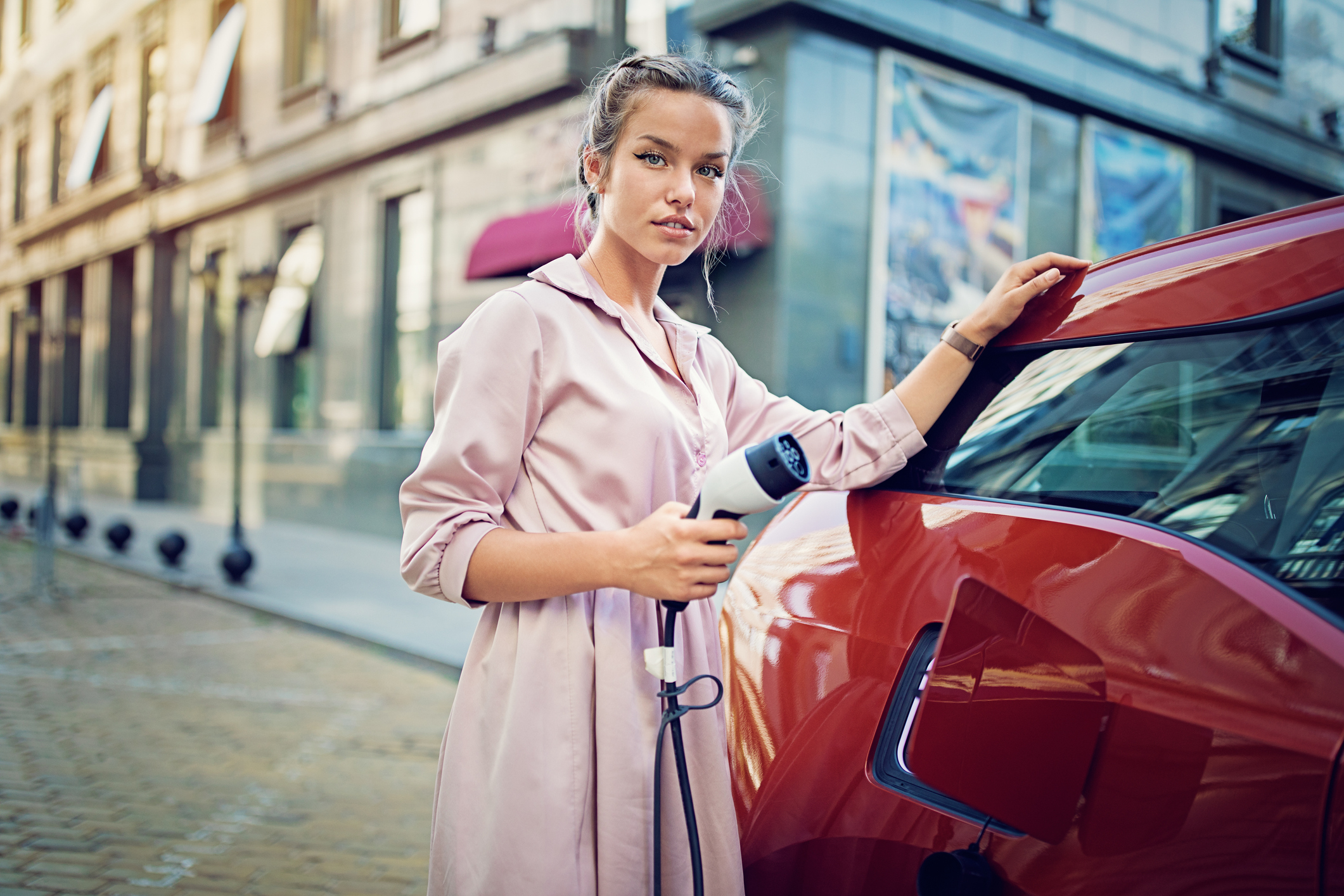 An electric vehicle driver charging a car.