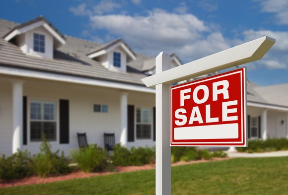 A "For Sale" sign outside of a house.