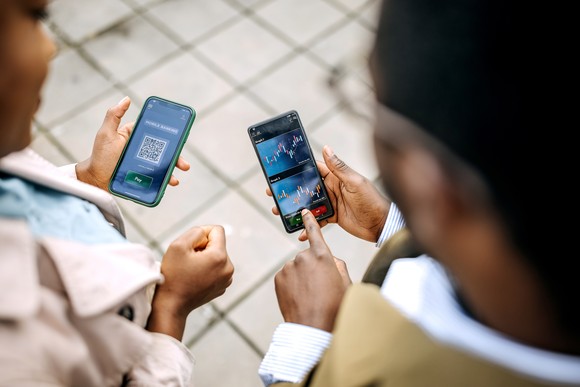 Two people looking at stock charts on their cellphones.