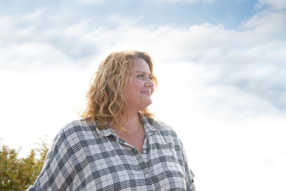 A person looking out into the distance with a bright, cloudy sky in the background. 