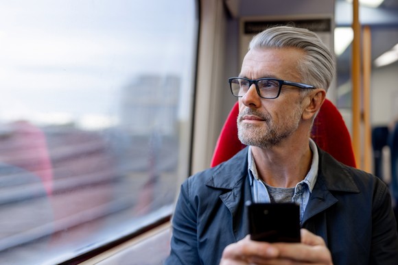 Someone is on a train or bus, looking out the window pensively.