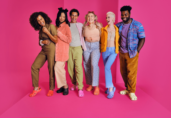 Six people showing off their Crocs shoes.