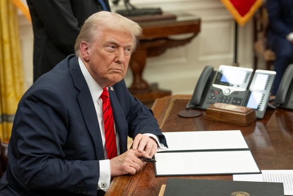 Donald Trump signing an executive order in the Oval Office.