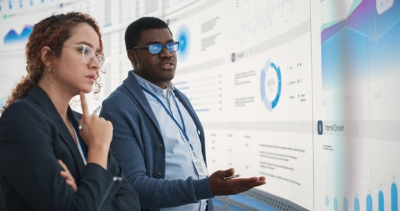 Data analysts looking at data on a big screen.