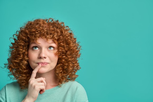 Someone with their finger on their lip in a thinking pose.