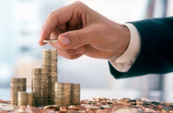 A person wearing professional attire stacks coins into towers. 