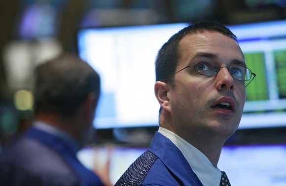 A New York Stock Exchange floor trader looking up in awe at a computer monitor. 