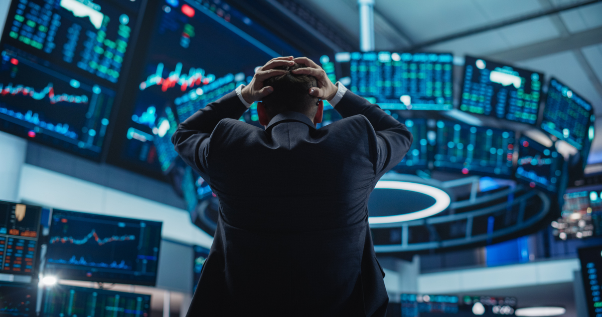 Person stands on the trading floor of a stock exchange with hands on head.