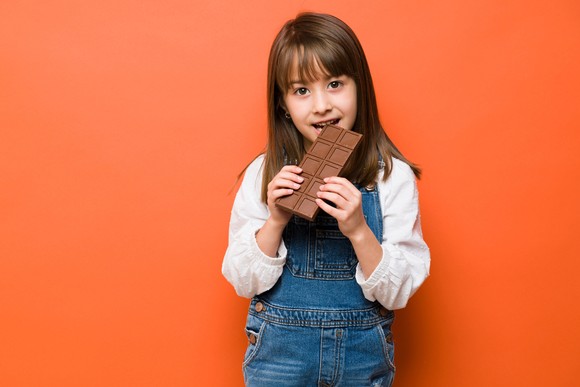 A child eating a large bar of chocolate.