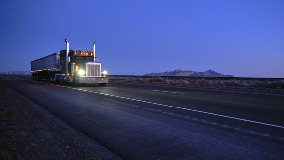 A truck driving on the highway at dusk.