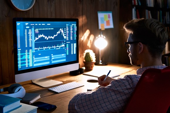 Person looking at charts on a computer screen in a dark office.