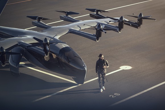 a person walks on the tarmac in front of an Archer Aviation Midnight model vertical lift short-haul aircraft