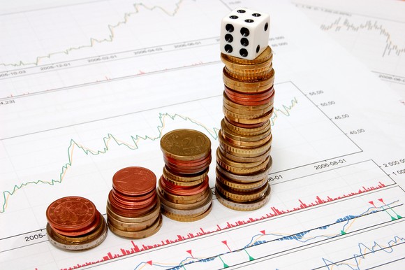 Rising stacks of coins with a die on top.