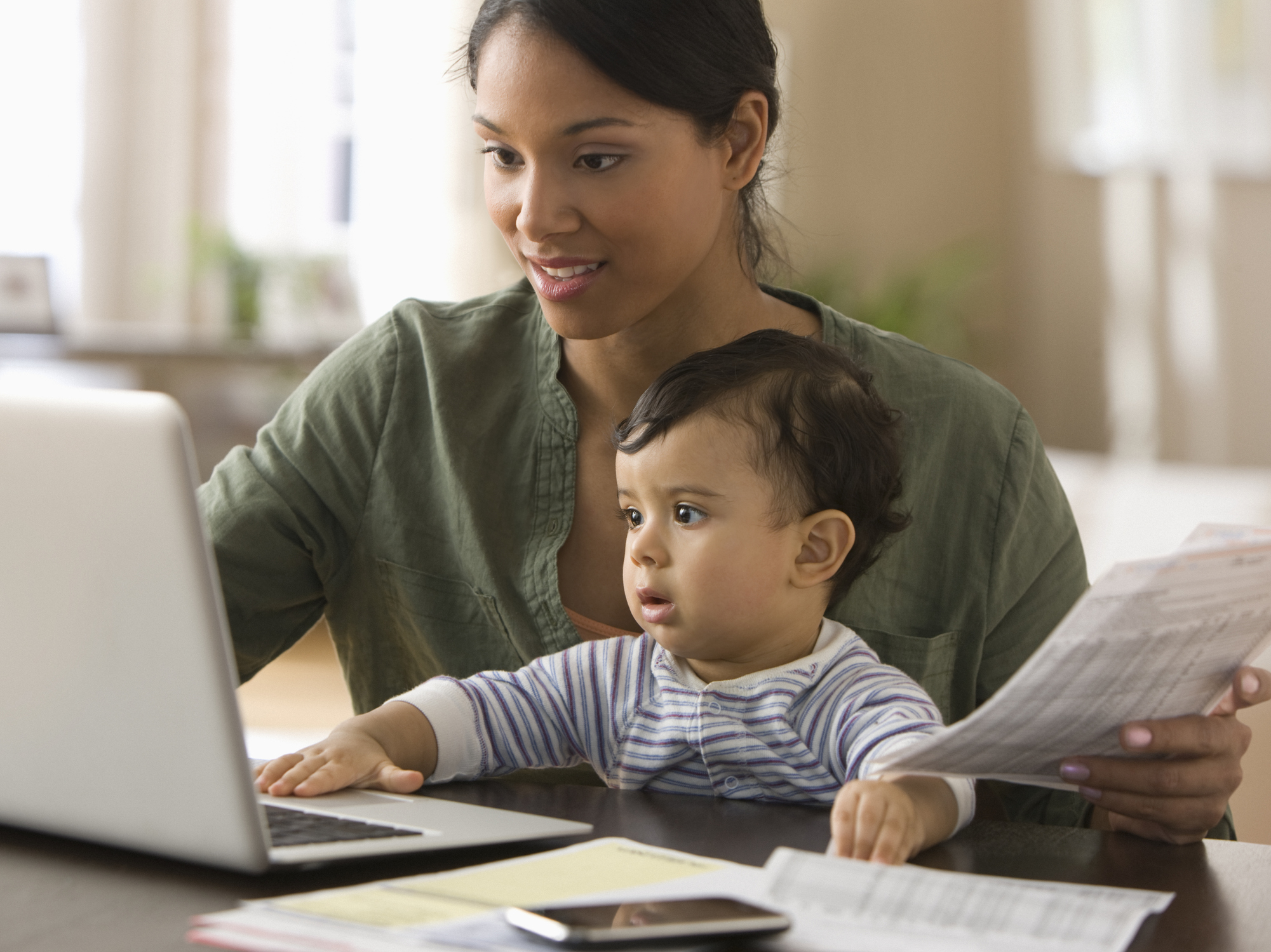 A person sitting with their child looking at a laptop.