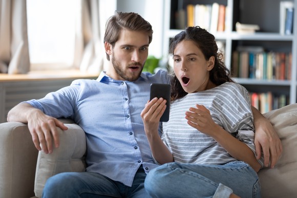 A surprised couple looks at a phone.