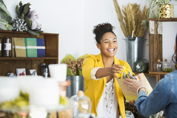 Small business owner handing a purchase to a customer.