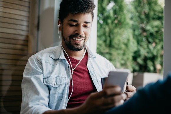 A person looking at their smartphone and listening to headphones.