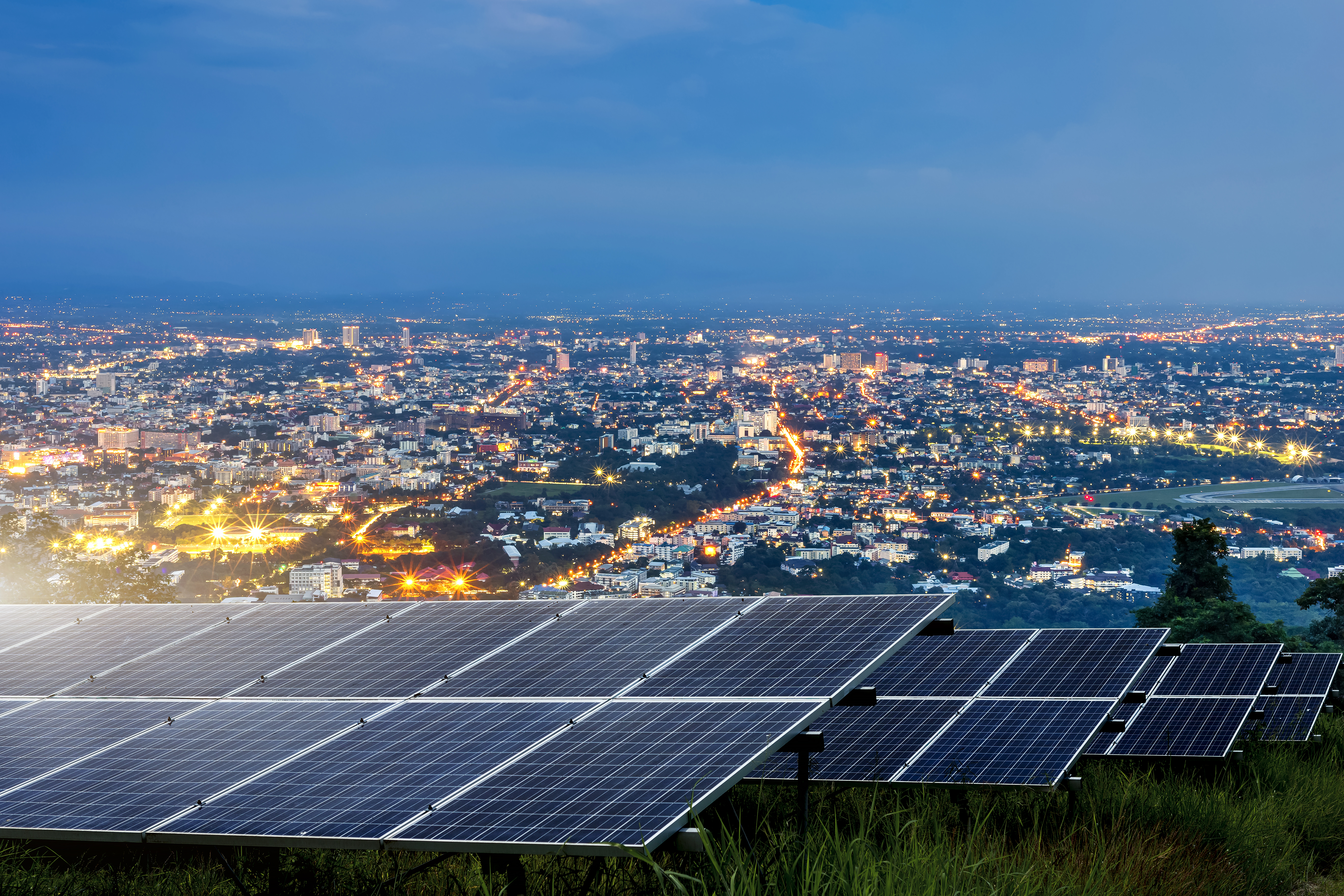 Solar panels with a nightime city backdrop.