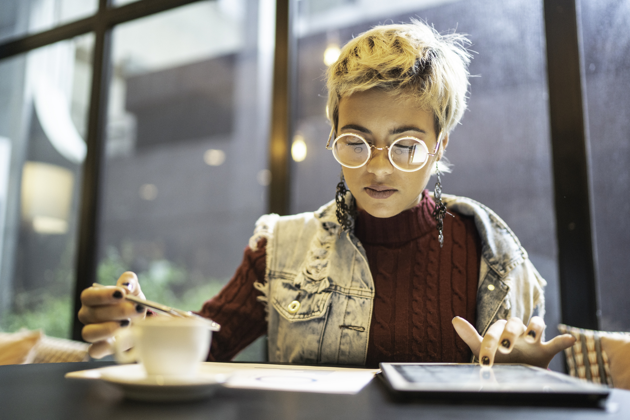 Person sitting in coffee shop looking at tablet.