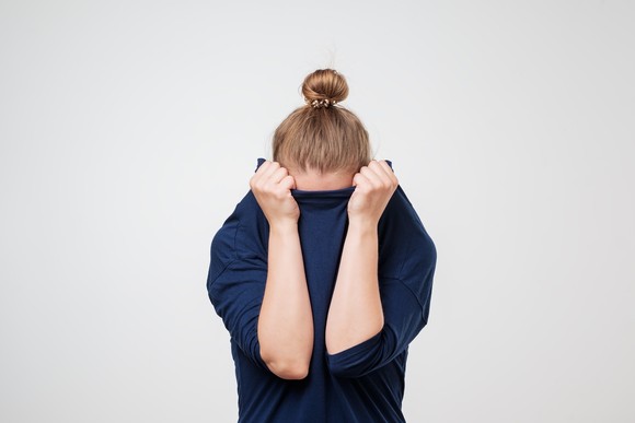 Person holding shirt over face.