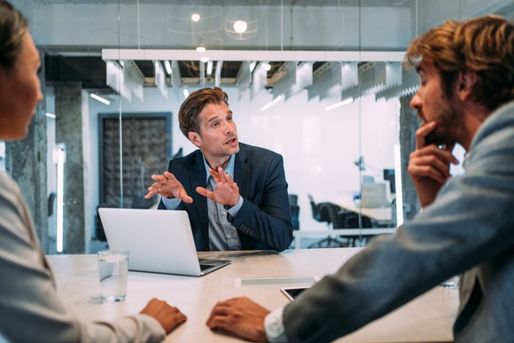 Person explaining something to two other people.