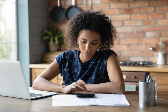 Adult sitting in their kitchen and looking at financial paperwork. 