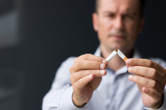 A person breaking a cigarette in half.