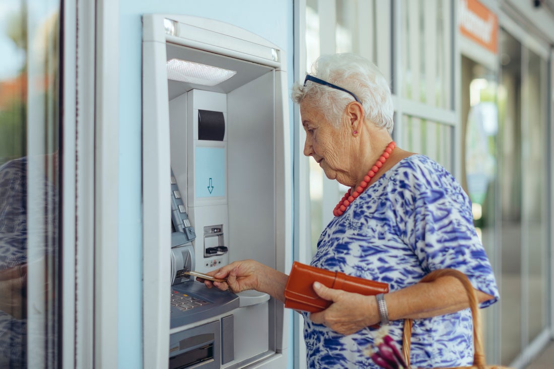 Elderly woman taking cash from an ATM.