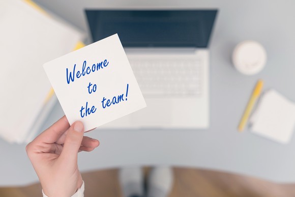 A hand holds a note that says Welcome to the team!