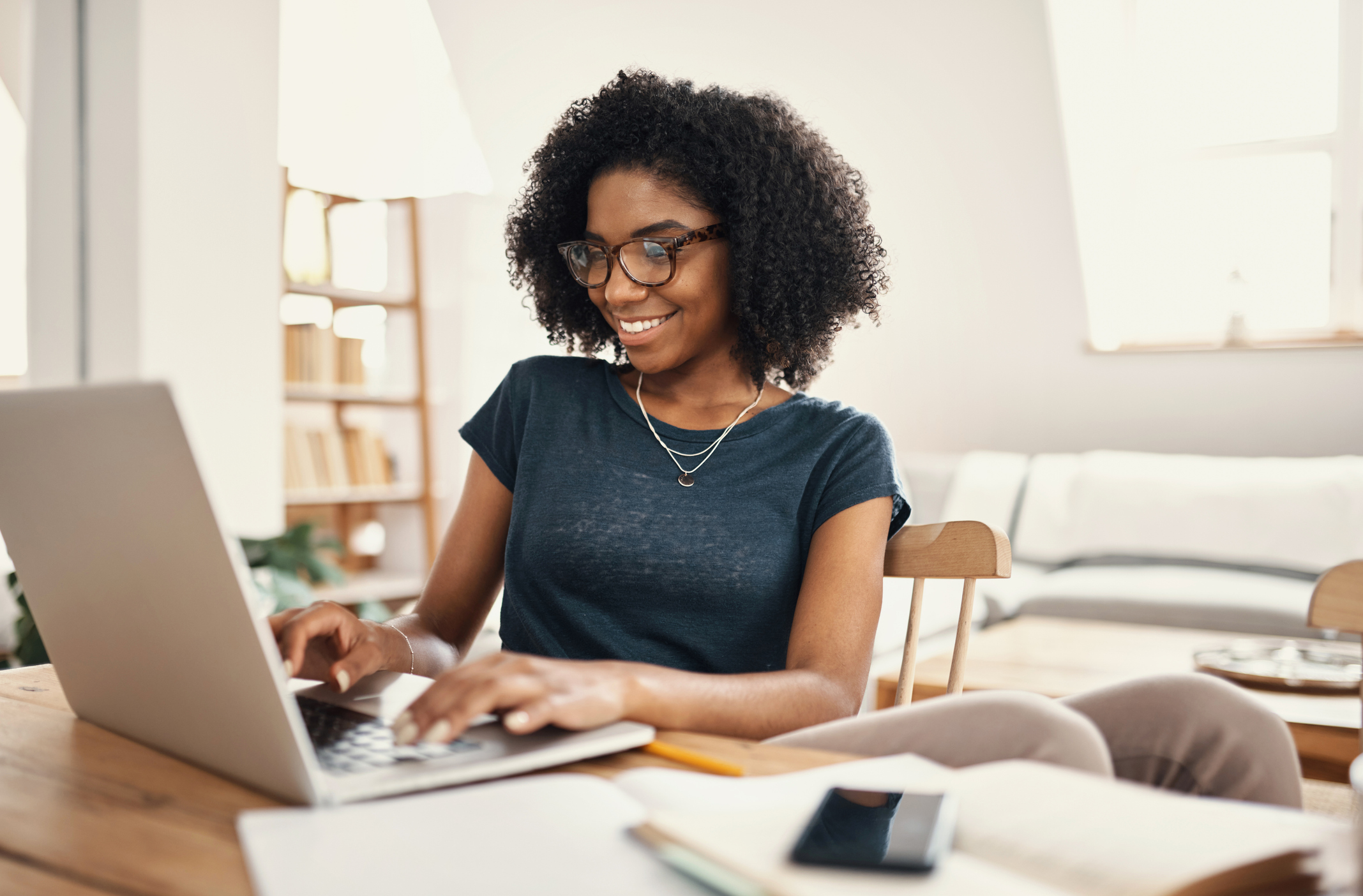 An investor smiles while working on a laptop at home.