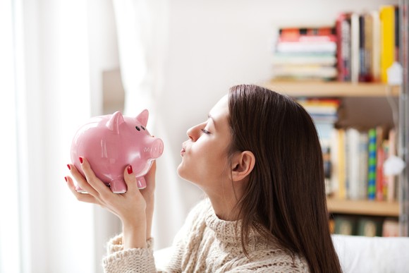 A young person holding up a piggy bank.