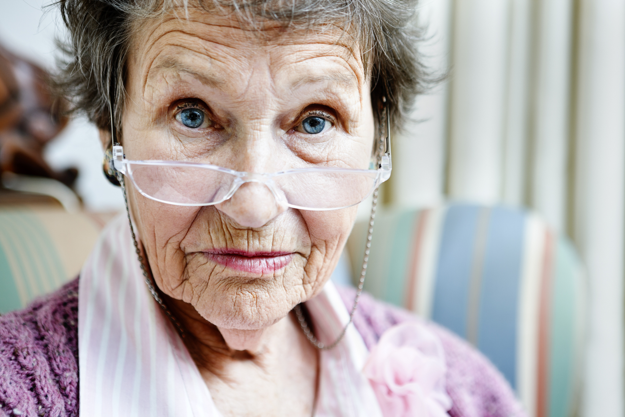 A person looking over glasses on the bridge of their nose.
