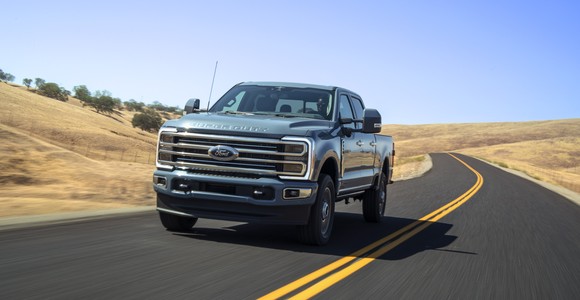 A Ford F-350 Super Duty truck driving on a one-lane road in the countryside. 