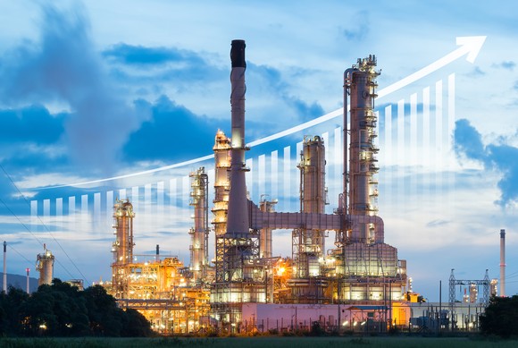 A chart rising behind an oil and gas facility.